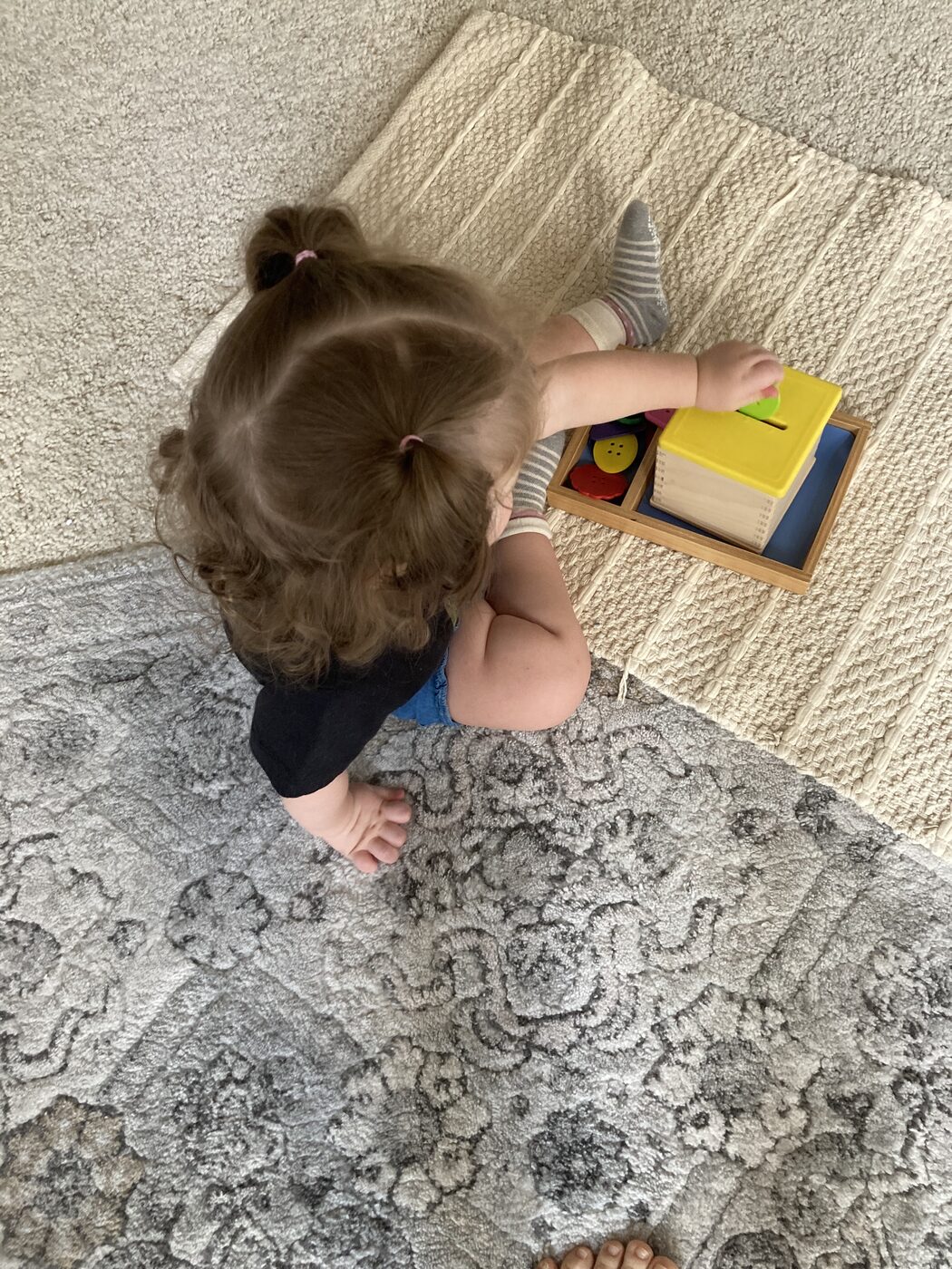Toddlers working with Montessori materials on a rug